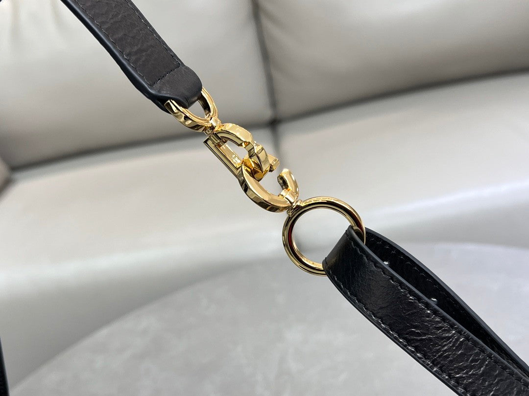 Distinctive black armpit bag, accentuated by metal accessories, a must - have for chic style.